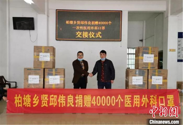 图为柏塘乡贤邱伟良几经波折购买的40000个一次性医用外科口罩，无偿赠送给柏塘镇奋斗在一线的工作人员，并由其侄子邱伟豪代为转赠现场 博罗县委宣传部供图 摄